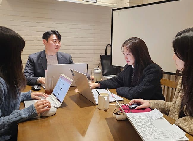 노트북을 펴고 키워드 자료를 짚어가며 이야기하는 팀원들
