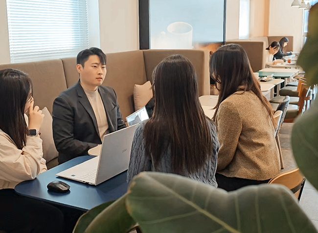 카페형 회의 공간에서 플라톤마케팅 담당자가 노트북을 앞에 두고 맞은편 세 사람에게 설명하는 모습